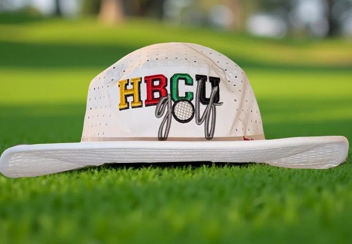 Cream HBCU Golf bucket hat on the grass.