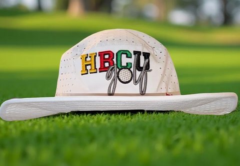 Cream HBCU Golf bucket hat on the grass.